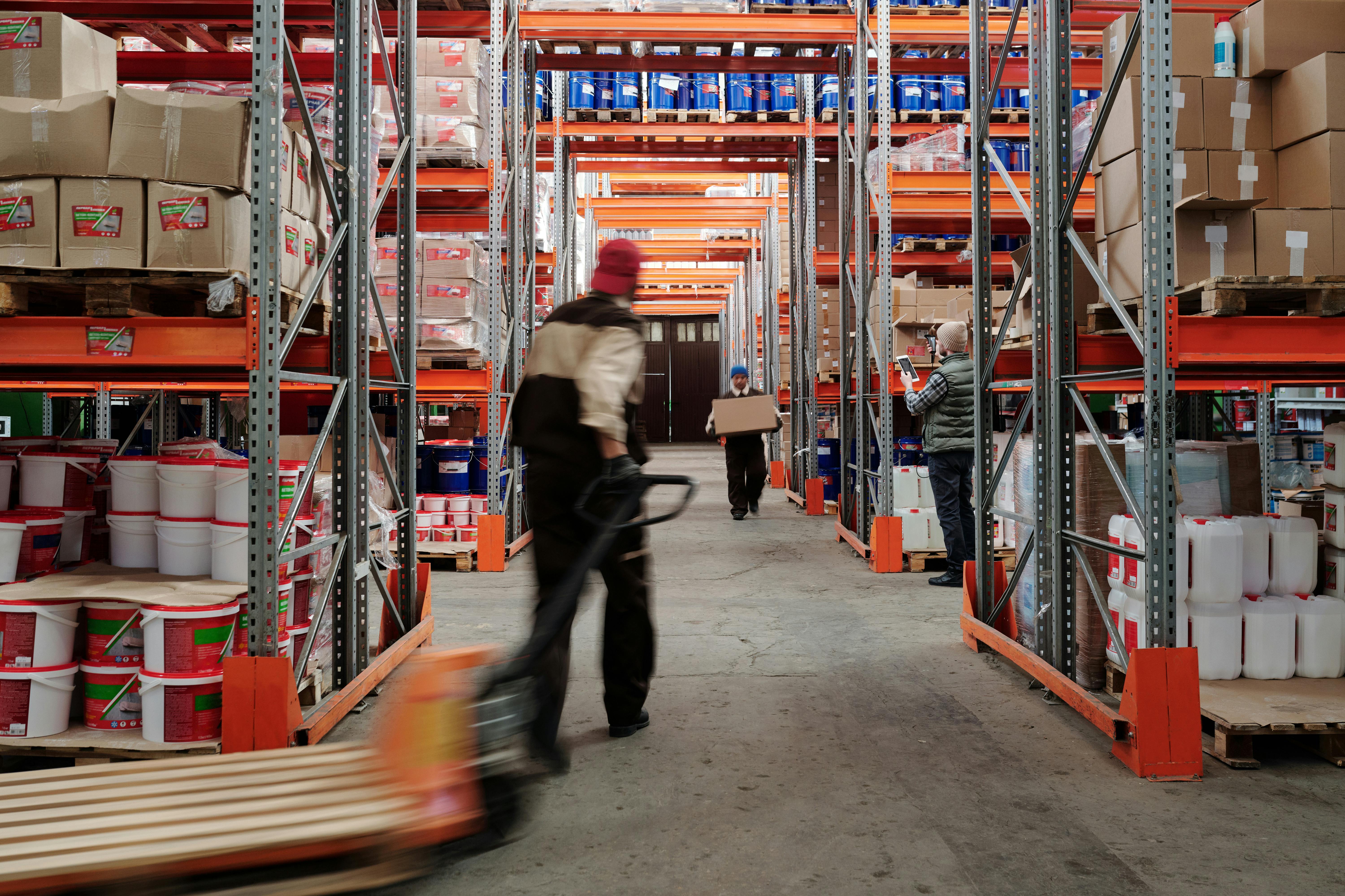 Warehouse workers moving through a stocked logistics aisle